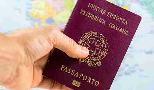 Hand holds an Italian passport with a blurred map in the background