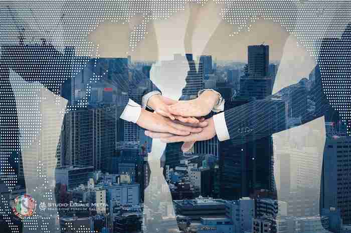 Business men joiniing their hands while in the background there is a picture of a city and the watermark of a world map